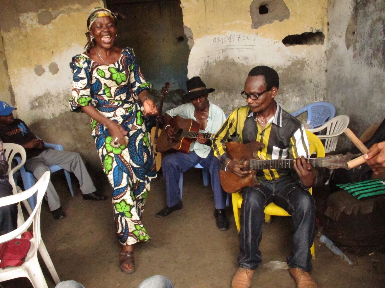Members of the band Bakolo Music International rehearsing with guitars while a singer dances, Kinshasa