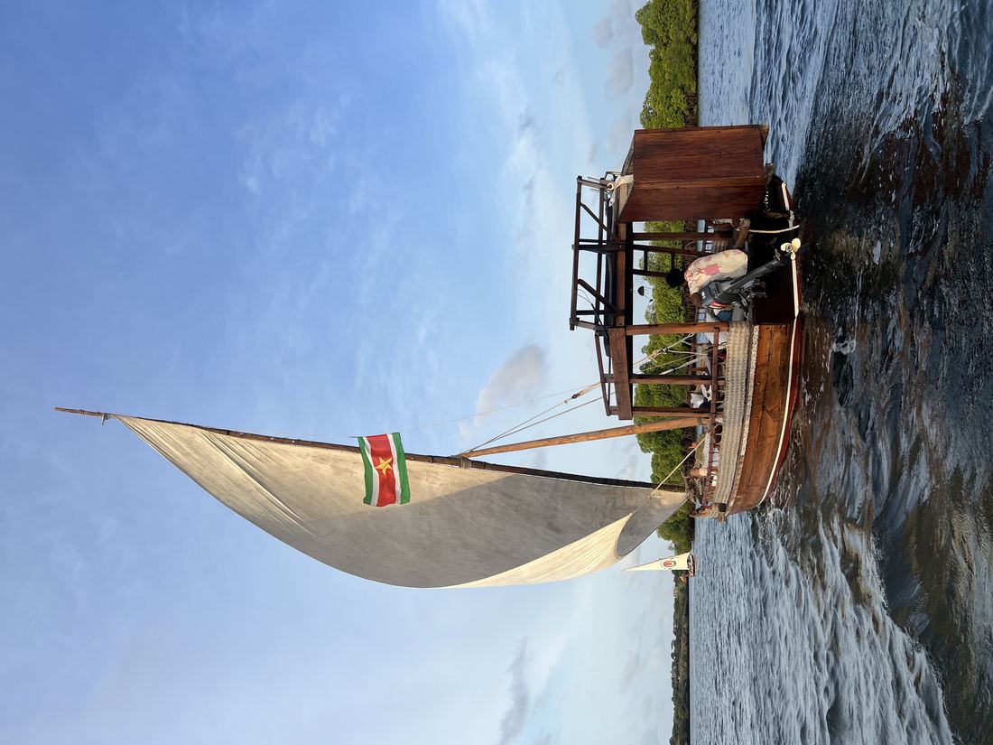 A wooden dhow with a triangular sail in the harbour at Lamu