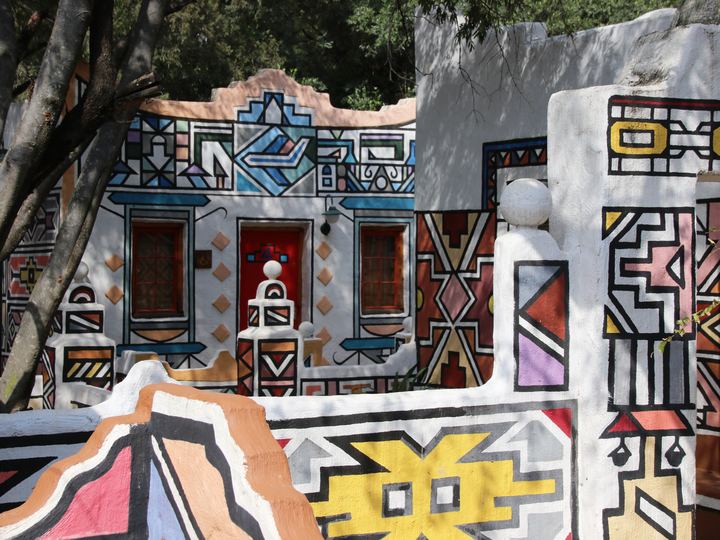 Walls of a homestead painted with bold geometric Ndebele patterns in black, white and bright colors