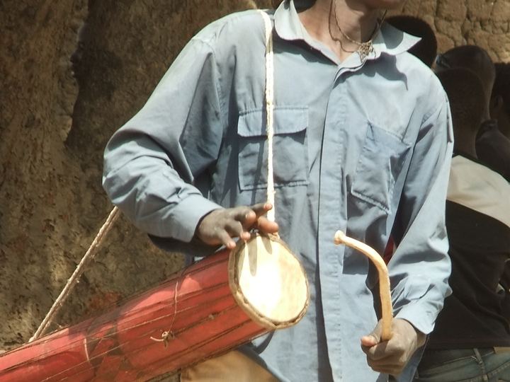 A musician playing a tama, an hourglass talking drum held under the arm