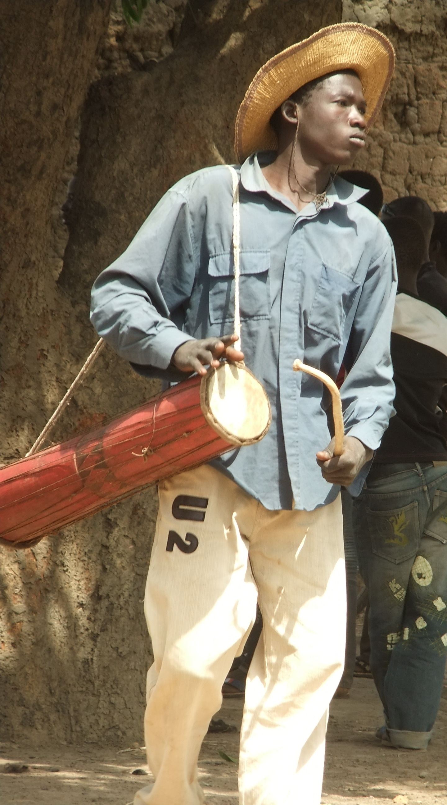 A musician playing a tama, an hourglass talking drum held under the arm